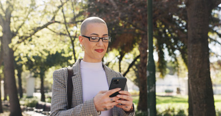 Phone, reading and business woman in park for communication, social media and search. Commute, networking app and connection with person and mobile outdoor for professional, contact and travelの写真素材