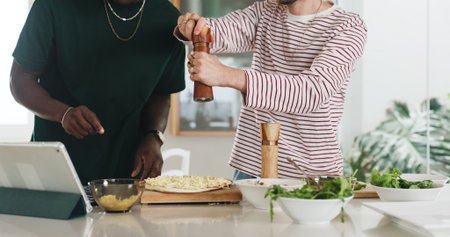 Hands, people and cooking with tablet at house for online recipe, meal prep and organic ingredients. Friends, digital and seasoning for Italian pizza, tutorial and culinary skills for homemade lunchの写真素材