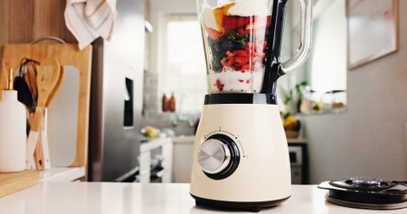 Fruits, blender and table for smoothie in kitchen for healthy drink, protein shake and nutrition. Machine, counter and organic ingredients for weight loss, diet milkshake and detox benefits at houseの写真素材