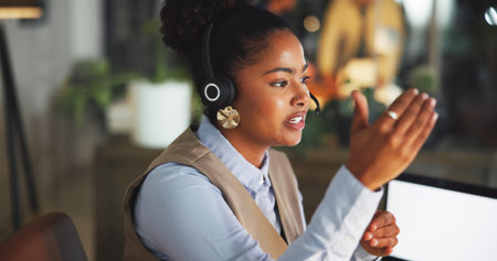 Contact us, woman and agent speaking in call center for help desk, support or feedback at night. Customer service, person or talk in office for virtual assistance, explain solution or crm on overtimeの写真素材