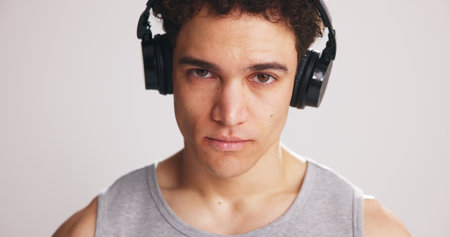 Portrait, athlete and man with headphones in studio for fitness, listening to music and podcast. Male person, streaming song and playlist audio for exercise, training motivation and white backgroundの写真素材