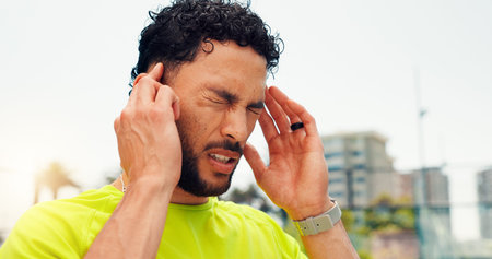 Frustrated man, headache and sport with vertigo in city for dizziness, mental health or strain....