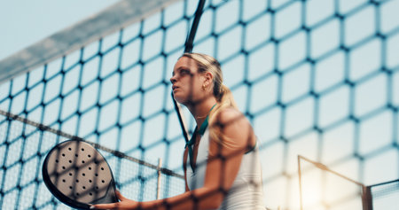 Padel tennis, net and woman outdoor for fitness, training and performance. Court game, cardio and workout or club competition with person in match for athlete, exercise and low angle of tournamentの写真素材