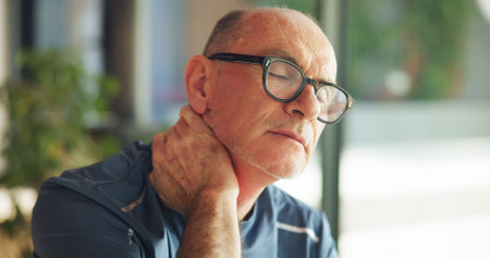 Living room, neck pain and senior man with tension, massage or discomfort of injury from bad posture. Retirement, stiffness and joint issue with osteoarthritis, muscle strain and old person in houseの写真素材