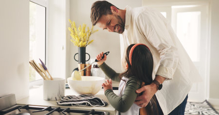 Bake, father and girl in kitchen, help and bonding together with happiness, learning and ingredients. Family, smile or parent with dad, daughter and cooking with recipe, home or support with utensilsの写真素材