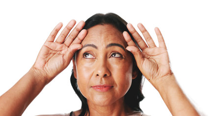 Mature woman, wrinkles and thinking in studio with forehead, check and squeeze on white background....