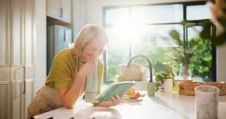 Senior woman, tablet and happy in kitchen with search, recipe and online course for dinner at house....