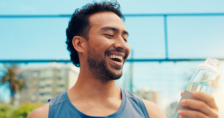 Tennis player, happy man outdoor and bottle with water, sports hydration and competition break. Smile, person and padel athlete on court with beverage for electrolytes, tournament rest and recovery.の写真素材