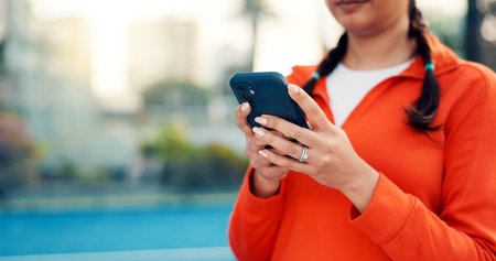 Hands, person and reading with phone on tennis court with fitness app, training tips and track progress. Woman, mobile and reservation for padel, technique and video demonstration of tournament matchの写真素材
