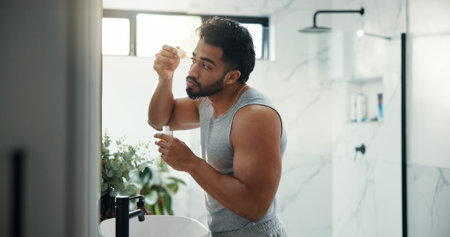 Man, dropper and serum for skincare in bathroom for hydration, beard growth and self care. Male...