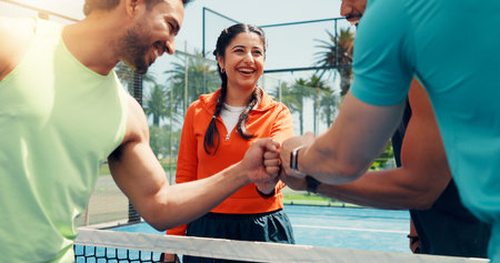 Woman, team and fist bump for padel, sports and excited for celebration, success or challenge for game. Men, athlete and friends at match, training or achievement with contest on tennis court at clubの写真素材