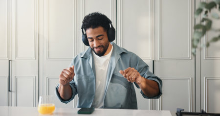 Dance, headphones and phone with man in kitchen of home for audio streaming or entertainment. App, music and rhythm with happy person at counter in apartment for listening, me time break or relaxの写真素材