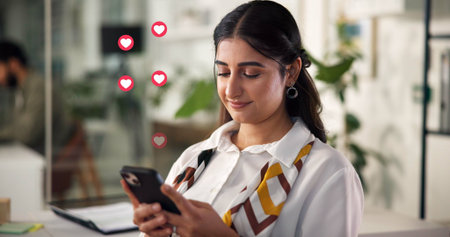 Happy woman, chatting or texting with heart icons for social media, network or review in office. Female person, employee or user with mobile smartphone app for online communication, like or reactionの写真素材