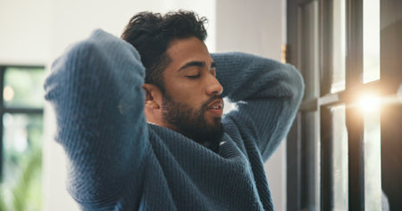 Fail, mistake or regret with man in home living room for choice, decision or problem solving. Hands behind head, stress and thinking with unhappy person in apartment for crisis, grief or lossの写真素材