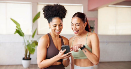 Fitness, women and friends with phone in yoga class for funny post, show meme and laughing. Pilates break, people and smile with smartphone at health club for comic video, humor and exercise gossipの写真素材