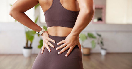 Hands, back pain and woman in studio, fitness and stretching with muscle fatigue. Burnout, exercise...