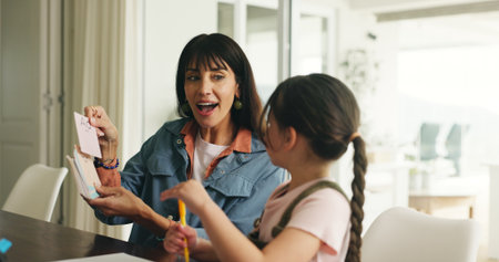 Homework, alphabet card and mother with girl in home for lesson, learning and help with activity. Family, language and mom with child, phonics and education for studying and teaching letters in houseの写真素材