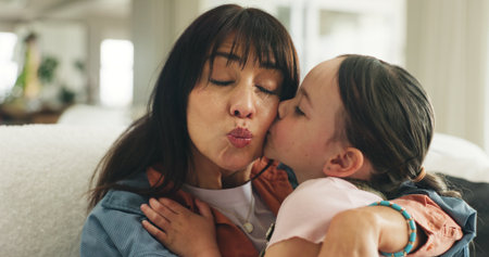 Relax, kiss and mother with daughter on sofa of family home for bonding, support and love. Connection, happiness and affection with woman and child in living room of apartment for trust and careの写真素材