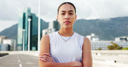 Crossed arms, fitness and portrait of woman in city with confidence for exercise, training and sports. Runner, athlete and serious person in urban town for wellness, challenge and health outdoorの写真素材
