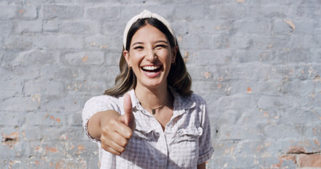 Happy woman, portrait and brick wall with thumbs up for fashion, style or feedback review on space....