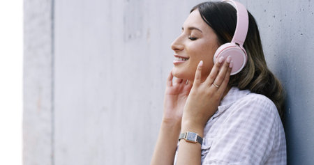 Happy woman, listening and music with headphones for vibe on a wall background or space. Calm,...