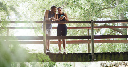 Bridge, smile and couple with cellphone, fitness and bonding together with social media. Outdoor and man in park, healthy woman and smartphone with training, laughing and digital appの写真素材