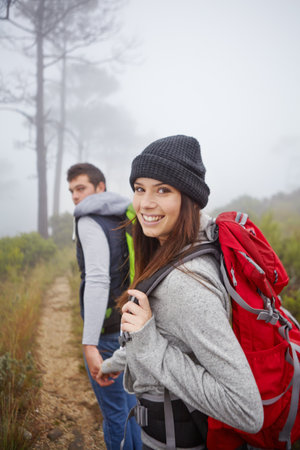 Smile, hiking and couple holding hands for travel, adventure or love with partner in nature. Happy woman, man and trekking in woods for vacation, portrait and holiday with fog in forest outdoorの写真素材