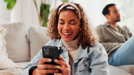 Couple, woman and laugh on sofa with phone for viral social media meme, text message and joke. Married, person smile and scroll with tech in home for online communication, internet humor and comedy.の写真素材