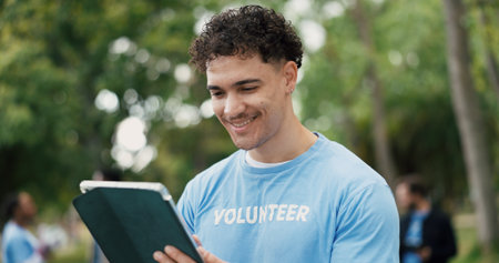 Happy man, volunteer or park with tablet for online campaign, donation or outreach in nature. Male person, activist or NGO with smile or technology for community service app, charity or eco startupの写真素材