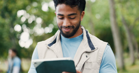 Smile, tablet and volunteer with man in park for charity, community outreach or food drive. App, planning and research with happy person outdoor for activism, ngo donation or non profit updateの写真素材