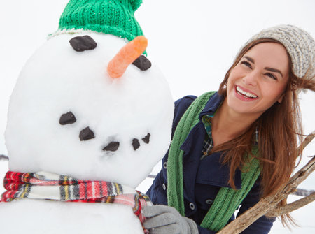 Snowman, smile and Christmas with woman outdoor for festive celebration, winter and game. Holiday tradition, happy and December vacation with female person in nature for xmas snow sculptureの写真素材