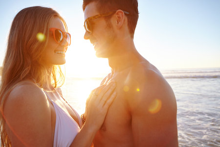 Happy couple, hug and sunset at beach on vacation, bonding and love for memory in relationship by ocean. People, smile and care with connection, trust and loyalty on holiday by sea for getawayの写真素材