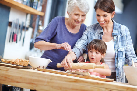 Grandmother, mom and child in house with baking, bonding and support in learning to cook. Happy, dessert and generations in kitchen with roller, family help or communication for childhood developmentの写真素材