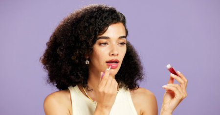 Application, beauty and lip gloss with gen z woman in studio for hydration or moisturizer routine....