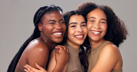 Happy women, portrait or hug with beauty, diversity or skin tone for cosmetics on studio background. Female people, inclusion or multiracial group with smile for skincare, health or wellness in salonの写真素材