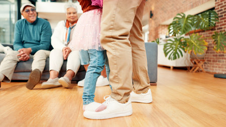 Family, dance and legs of parent with child in home for bonding, learning steps and relationship. Grandparents, living room and feet of kid with dad for dancer lessons, connection and fun togetherの写真素材