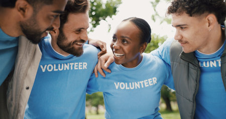 Volunteer, group and smile in huddle outdoor for community service, NGO and help for social responsibility. Support, team and happy people with talk for motivation, nonprofit and activism in parkの写真素材