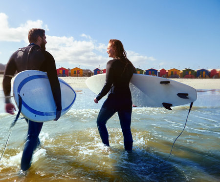 Surfer, couple and smile with beach, ocean and nature for walk or vacation fitness. Back of man, woman and surfboard with waves, cardio hobby and summer workout or tropical holiday for trip by seaの写真素材