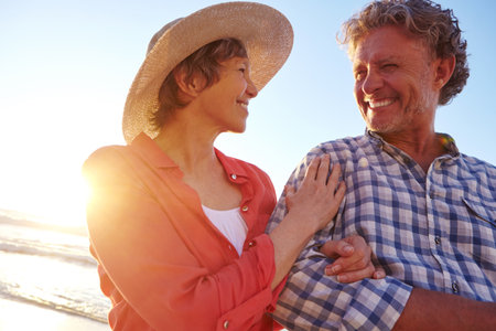 Smile, mature couple and walk on beach with love, travel date and bonding together on holiday. Happy, people and embrace with affection, romantic partner and anniversary getaway for tropical vacationの写真素材