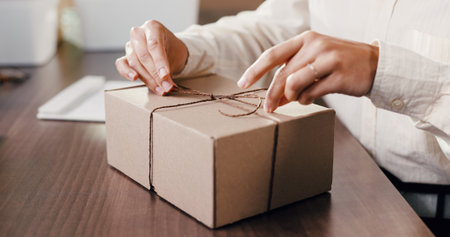 Hands, box and string at startup for dropshipping, eco friendly packaging and logistics for ecommerce order. Person, cardboard parcel and knot for stock, distribution or shipping at storage plantの写真素材