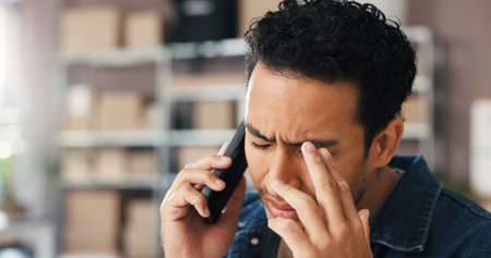 Logistics, man or phone call with stress in warehouse for delivery mistake, lost package or crisis. Frustrated, small business owner and speaking to client for shipping delay, wrong order and worryの写真素材