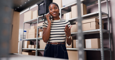 Below, black woman and phone call for logistics in warehouse for schedule, chat or contact supplier. Person, mobile and talking for shipping order, supply chain and customer inquiry for distributionの写真素材