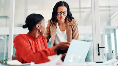 Meeting, business women and laptop in office for feedback, news report and teamwork. Discussion, creative employees and journalist in conversation for research, advice and article for proofreadingの写真素材