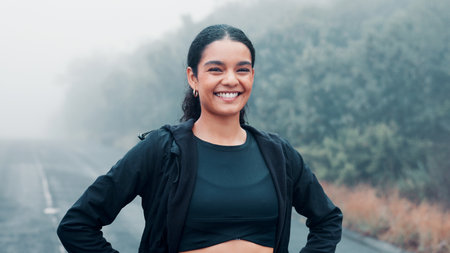 Nature, fitness and portrait of happy woman on road, marathon runner and ready for cardio training. Outdoor, morning mist and confident athlete smile for endurance practice, wellness or start workoutの写真素材