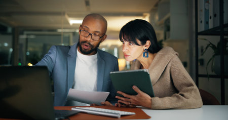 Laptop, team and business people in office for report, collaboration and feedback. Tech, drafting proposal and research with discussion for proofreading, review and editing publication at nightの写真素材