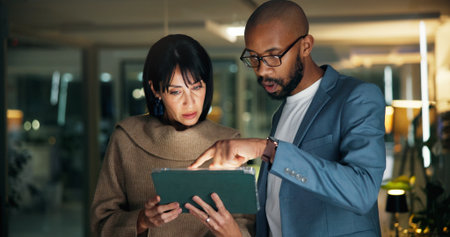 Tablet, planning and business people in office for report, collaboration and feedback. Technology, drafting proposal and research with team for proofreading, review and editing publication at nightの写真素材