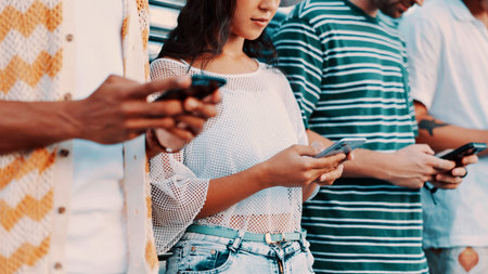 Hands, phone and text message with people outdoor together for connection or social media browsing. App, contact and typing with group of friends in line for communication, online chat or readingの写真素材