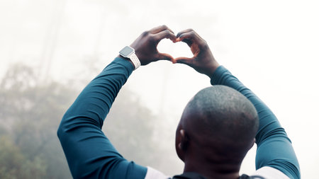 Black man, fitness and heart hands with mist in nature for outdoor training, health or wellness. Back view, active or male person in fog with emoji, sign or shape for love, exercise or winter workoutの写真素材