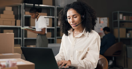 Headset, shipping and woman with laptop for customer support, order info or typing. Logistics, computer and worker with mic for call, supply chain assistance and delivery in small business officeの写真素材