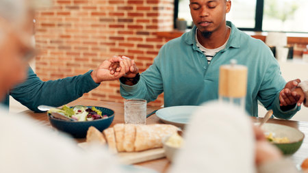 Family, dining or holding hands with praying for food, faith or thanksgiving dinner together in home. Man, grace and gathering with connection for god worship, gratitude or thankful for meal in houseの写真素材